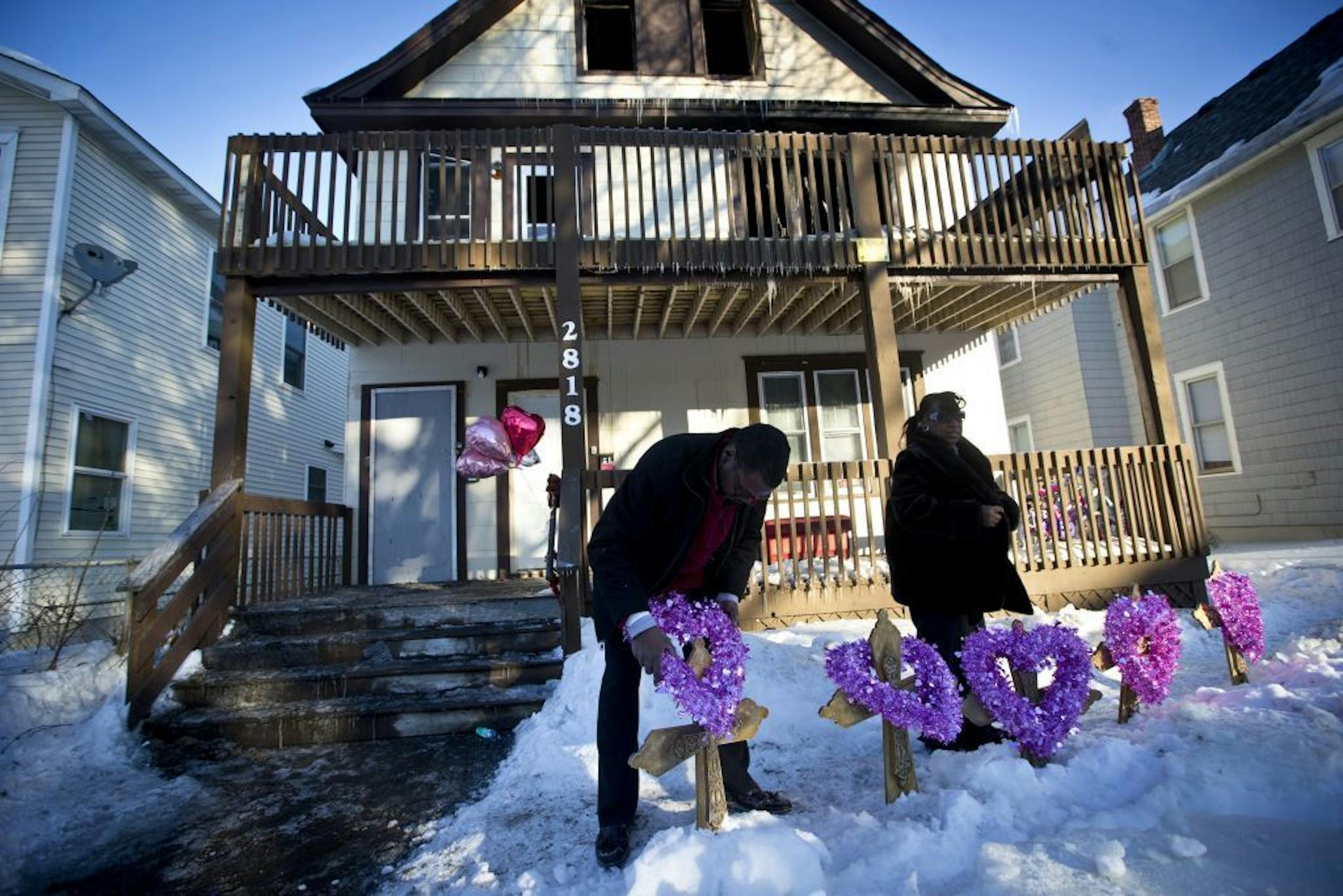 John Martin and Helen Williams put five crosses and wreaths in front of the home where five siblings were killed in an early morning house fire on Friday, February 14, 2014 in Minneapolis, Minn. John Martin was with the Minneapolis Federation of Teachers and Helen Williams runs a service to help people afford to bury their loved ones.