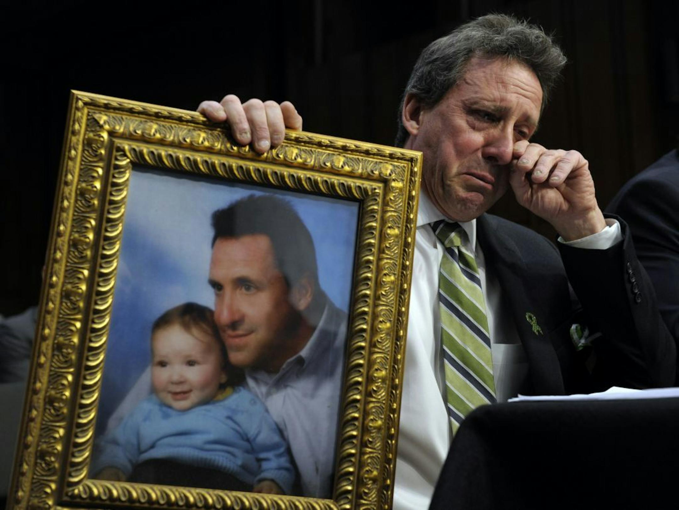Neil Heslin, the father of a six-year-old boy who was slain in the Sandy Hook massacre in Newtown, Conn., in December, wipes his eye while testifying in February before the U.S. Senate Judiciary Committee.