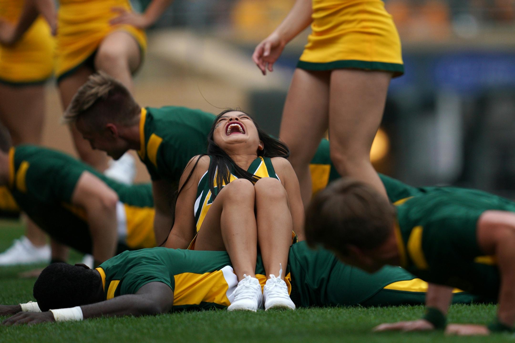 A cheerleader laughed as she sat on the back of a fellow cheerleader as he did pushups after North Dakota State Bison running back Kobe Johnson (24) ran the ball in for a touchdown in the second half.