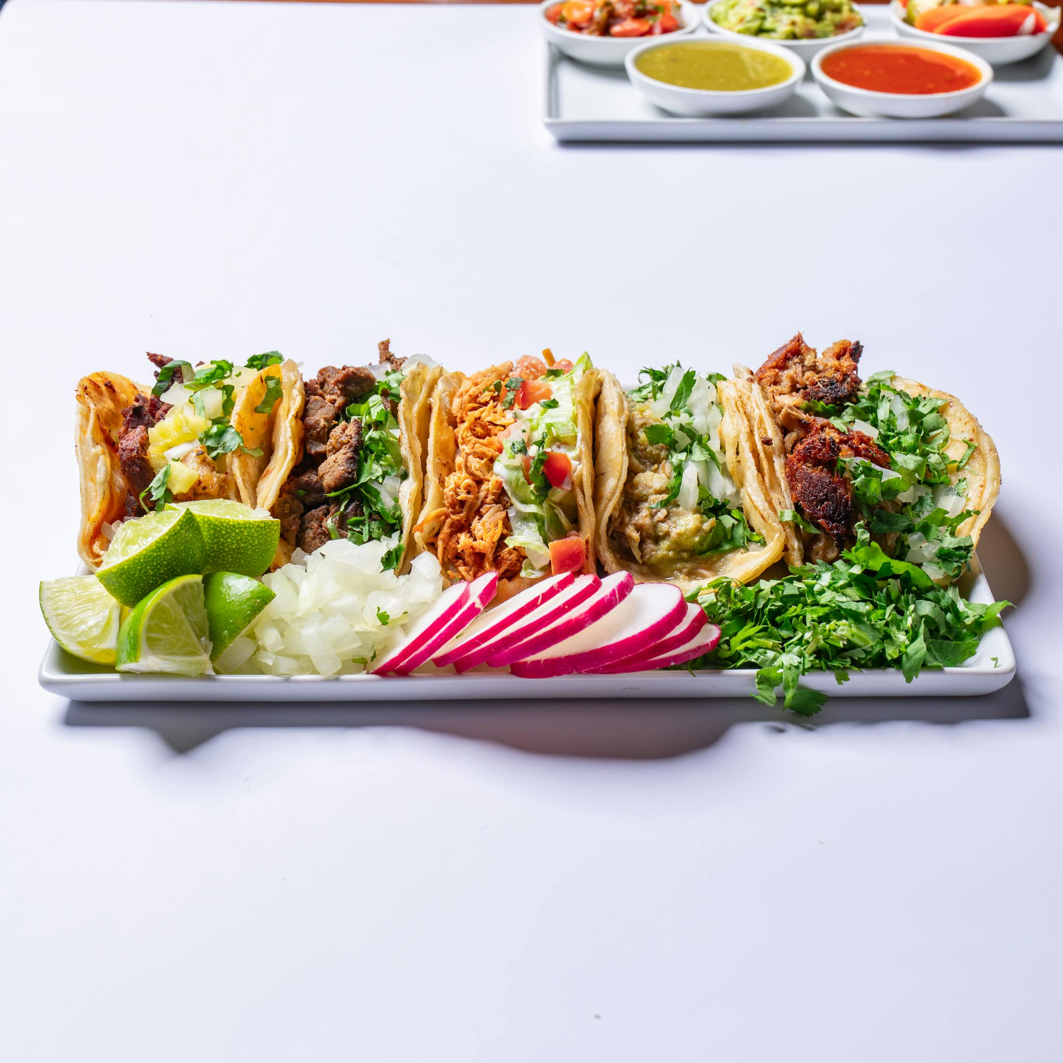 A tray filled with tacos and fresh garnishes.