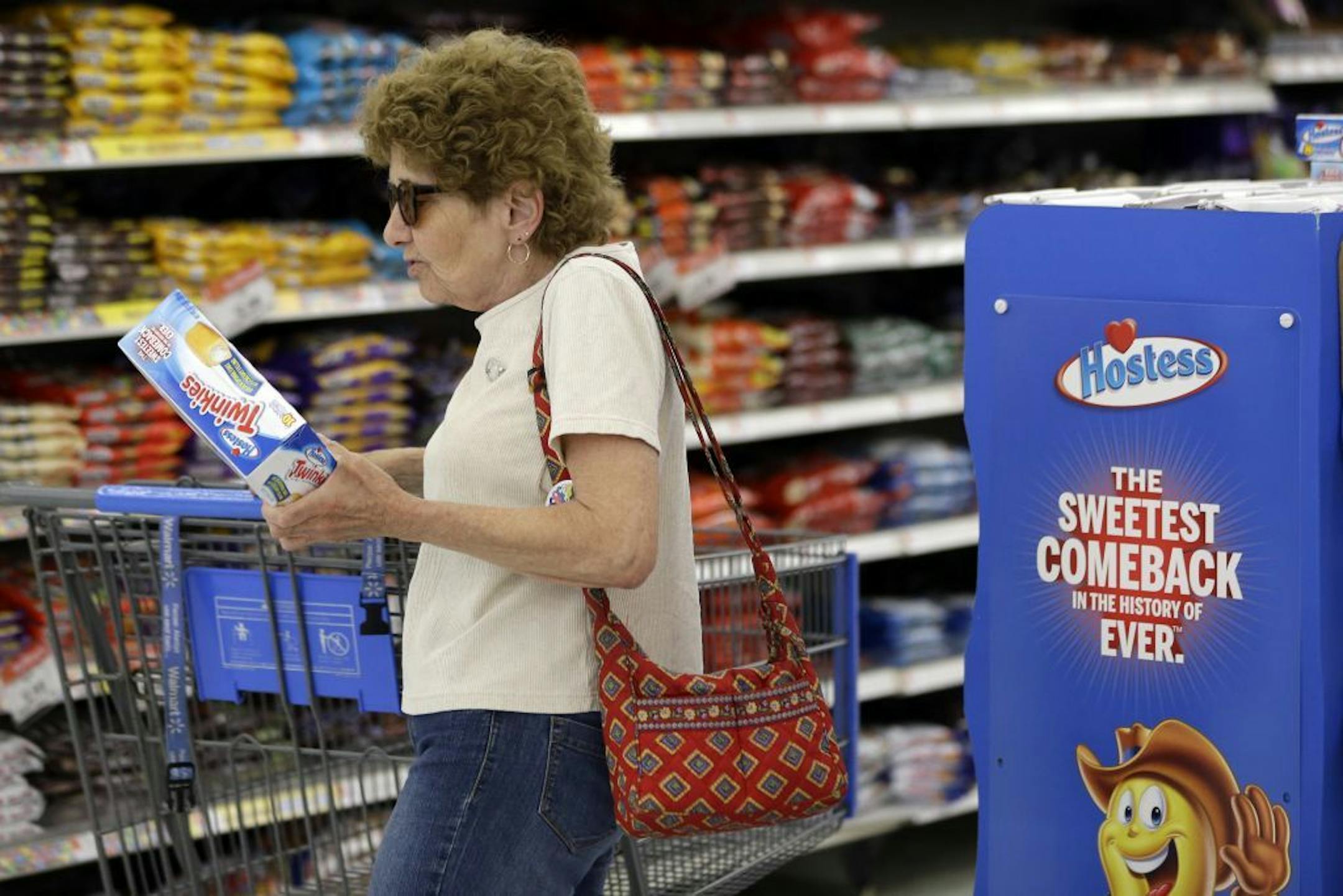 FILE-- In this Friday, July 12, 2013, file photo Jo Mullen picks up a box of Twinkies at Wal-Mart, in Bristol, Pa. The new owners of Hostess have leaner operating costs now that they're no longer using unionized workers. It turns out the spongy yellow cakes may also be a little smaller than the last Twinkies people remember eating.