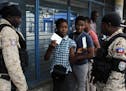 A voter shows her electoral documents to national police officers before entering a voting station in the Petion-Ville suburb of Port-au-Prince, Haiti