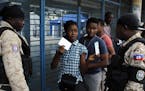 A voter shows her electoral documents to national police officers before entering a voting station in the Petion-Ville suburb of Port-au-Prince, Haiti