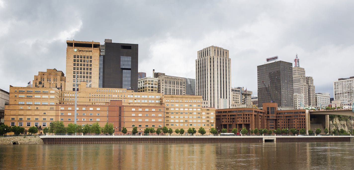 The former West Publishing building, long tan building on left, and former Ramsey County jail building, squat reddish-brown building on right, are seen from across the Mississippi River in downtown St. Paul on Friday, May 29, 2015. ] LEILA NAVIDI leila.navidi@startribune.com / BACKGROUND INFORMATION: This June, Ramsey County will begin razing the former West Publishing building and Ramsey County jail along the St. Paul's downtown river bluff to make way for a sale and new development of the area