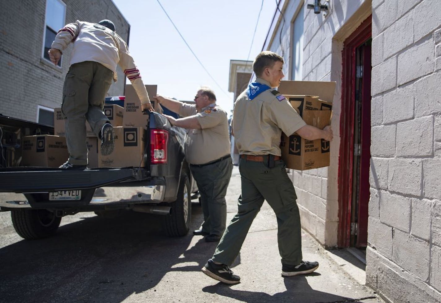 (Left) CHUM Distributive Services Director Scott Van Daele, Arrowhead District Director Clark Garthwait and Life Scout Seth Werner worked to carry the boxes of popcorn into the CHUM food shelf on Tuesday.