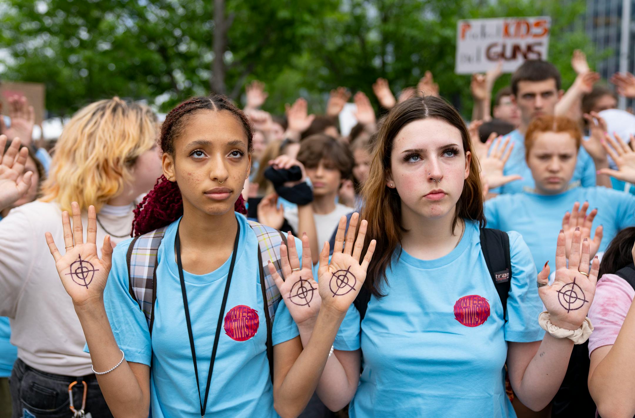 Aesha Graffunder, a junior at Roosevelt High School, and Cohen Rivard, a junior at FAIR High School, hold up their hands as they listen to speakers during a student walkout and march to protest gun violence.