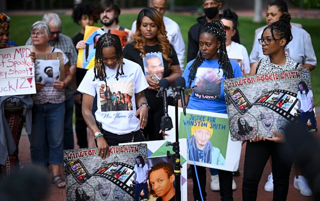 Shatana Cooper, left, of center, held a photo of her brother Winston Smith beside family members at a rally outside the Hennepin County Government Cen