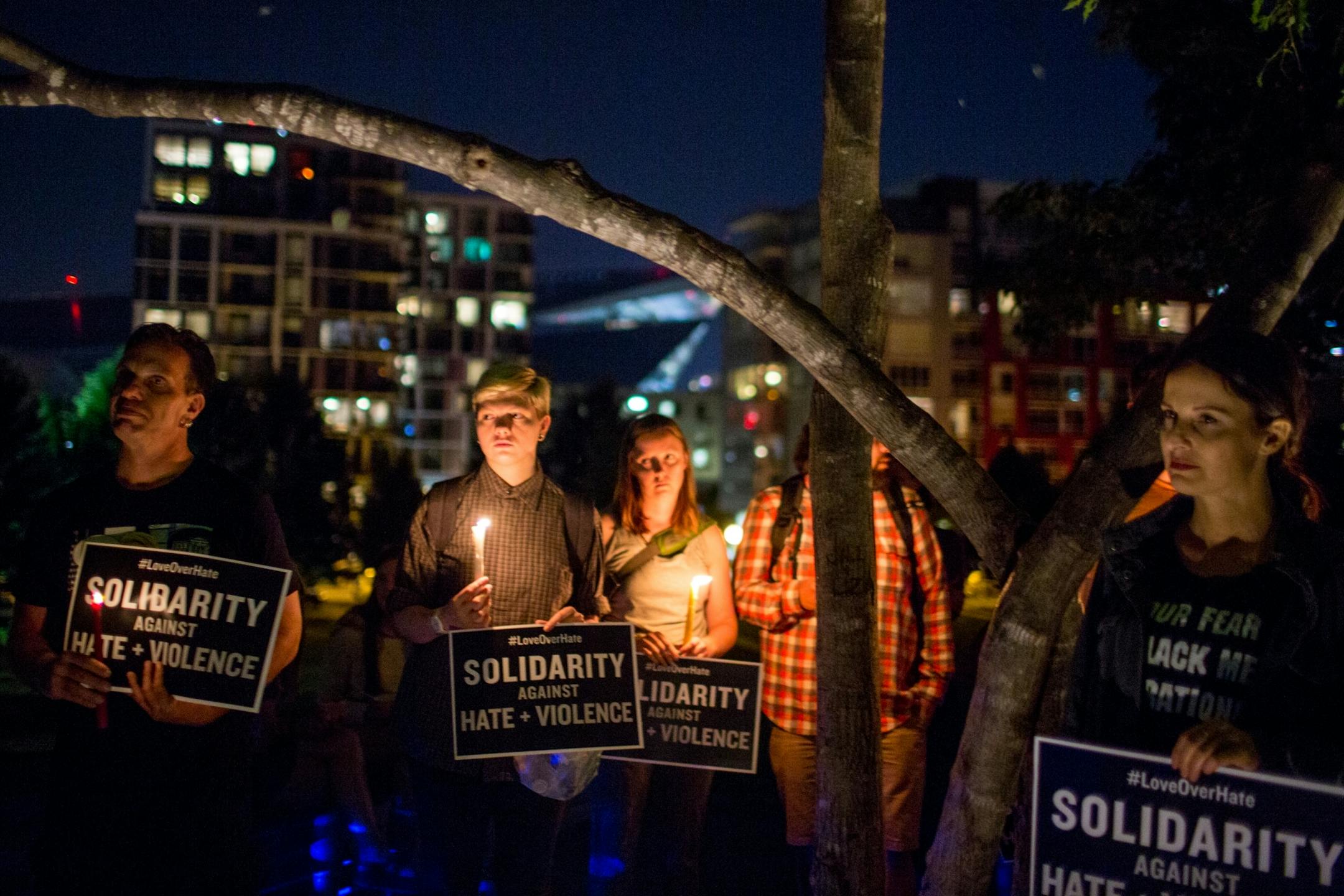 People stand atop a hill for a candlelight vigil in solidarity with Charlottesville counter protesters at Gold Medal Park, on Saturday night.