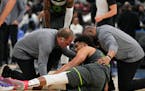 Two team staff members attend to Minnesota Timberwolves center Karl-Anthony Towns after getting hurt during the second half of an NBA basketball game 