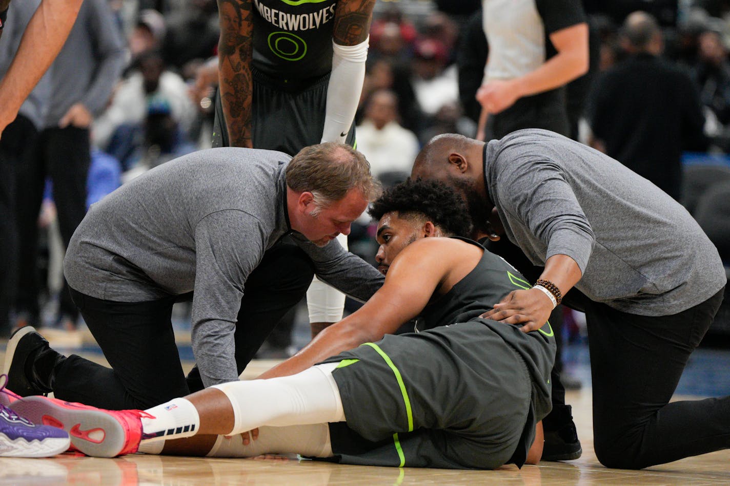 Two team staff members attend to Minnesota Timberwolves center Karl-Anthony Towns after getting hurt during the second half of an NBA basketball game against the Washington Wizards, Monday, Nov. 28, 2022, in Washington. (AP Photo/Jess Rapfogel)