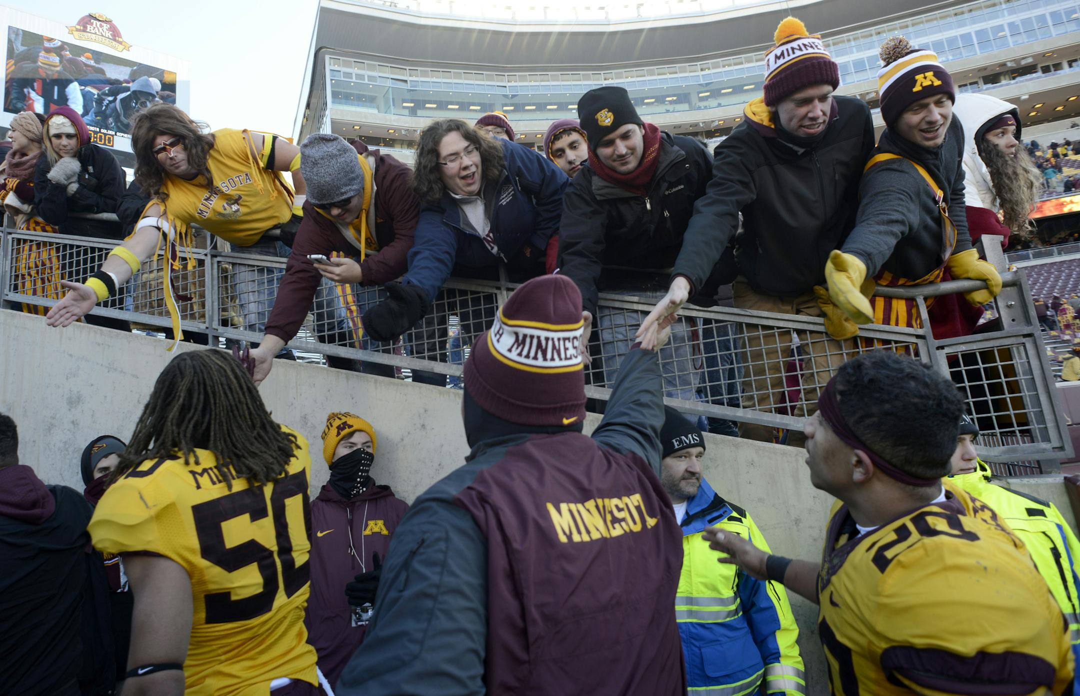 Minnesota's head coach Tracy Claeys, center, high-fives fans after a 32-23 win over Illinois in an NCAA college football game, Saturday, Nov. 21, 2015, in Minneapolis. (AP Photo/Hannah Foslien)