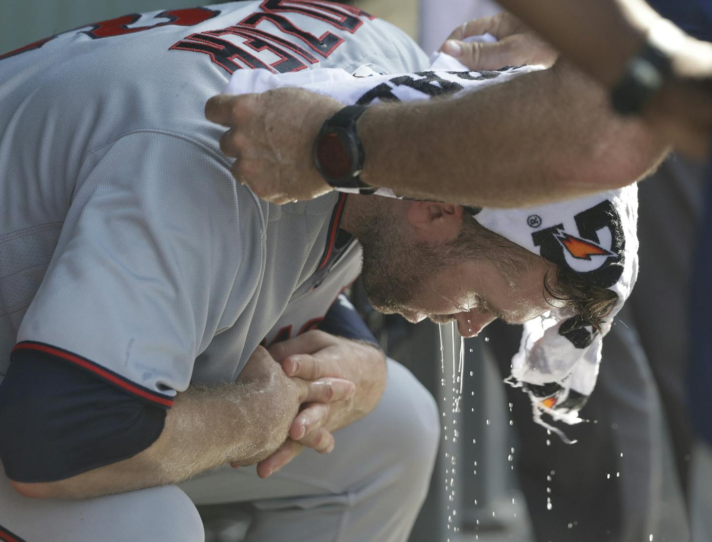 Minnesota Twins' Brian Dozier has a cold wet towel applied to his head during the seventh inning of a baseball game Chicago Cubs Saturday, June 30, 2018, in Chicago. Temperatures at Wrigley Field climbed into the mid 90's with a heat index over 100 degrees. (AP Photo/Charles Rex Arbogast)