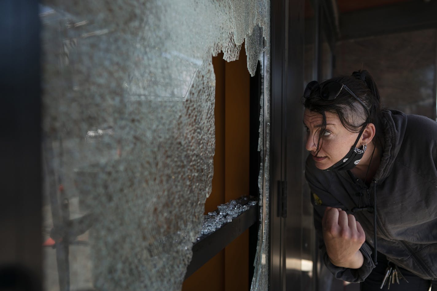 Megan Culverhouse, an employee at the John Fluevog shoe store in Uptown, cleaned up broken glass from a window hit by gunfire from an early morning shooting on Sunday, June 21, 2020, in Minneapolis.