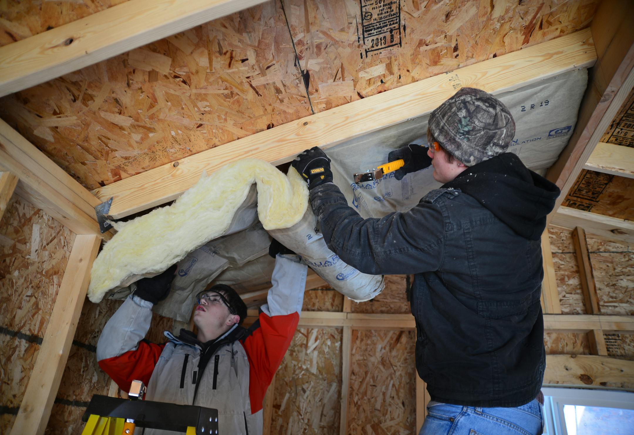 At Belle Plaine High School, students in a construction class are building a cabin, which will eventually be transported to a northeastern Minnesota campground so campers can rent it. The class provides hands-on experience with light construction for about a dozen students, who work in teams to learn about all aspects of building a small house. Belle Plaine High School students Taylor Wendt on the left and Travis LaTour insulated the ceiling of the cabin ] Richard.Sennott@startribune.com Richard