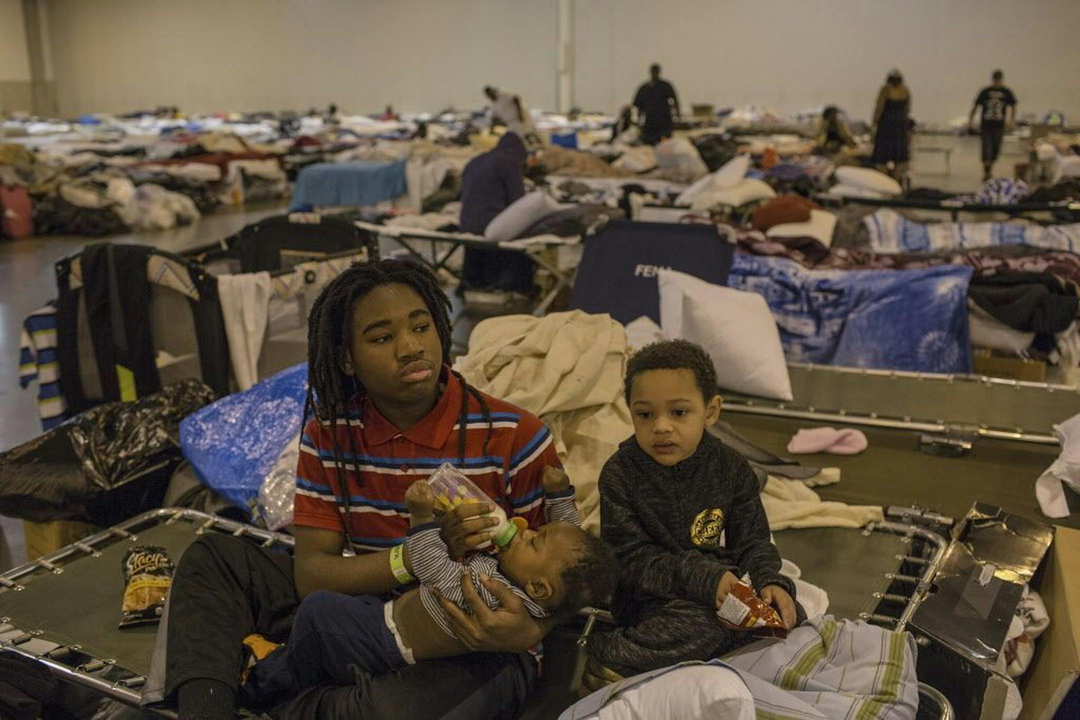 Quentin Bermard, 13, feeds his baby brother Qumajestyferd, 5 months, both evacuees from southeast Houston, at the makeshift storm shelter at the NRG Center in Houston, Sept. 3, 2017.