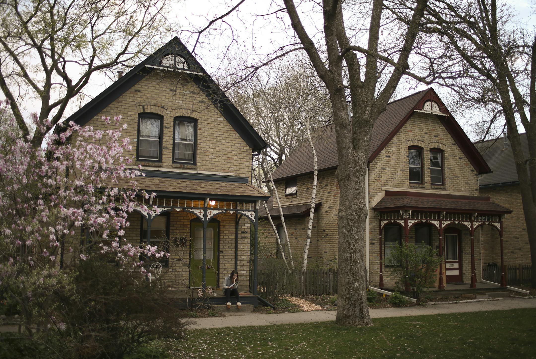 Natalie Peterson read and sipped tea on the porch of one of the preserved homes on Milwaukee Ave. dating to the 1880's, which Gar Hargens says was key to the revitalization of the Seward neighborhood.