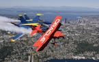 Team Oracle stunt pilot Sean Tucker, front, is joined by a pair of U.S. Navy Blue Angels during an air show practice run in view of downtown Seattle, 