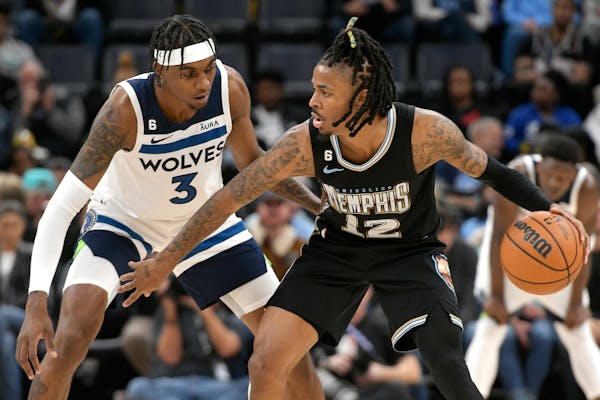 Memphis Grizzlies guard Ja Morant (12) is defended by Minnesota Timberwolves forward Jaden McDaniels (3) during the first half of an NBA basketball ga