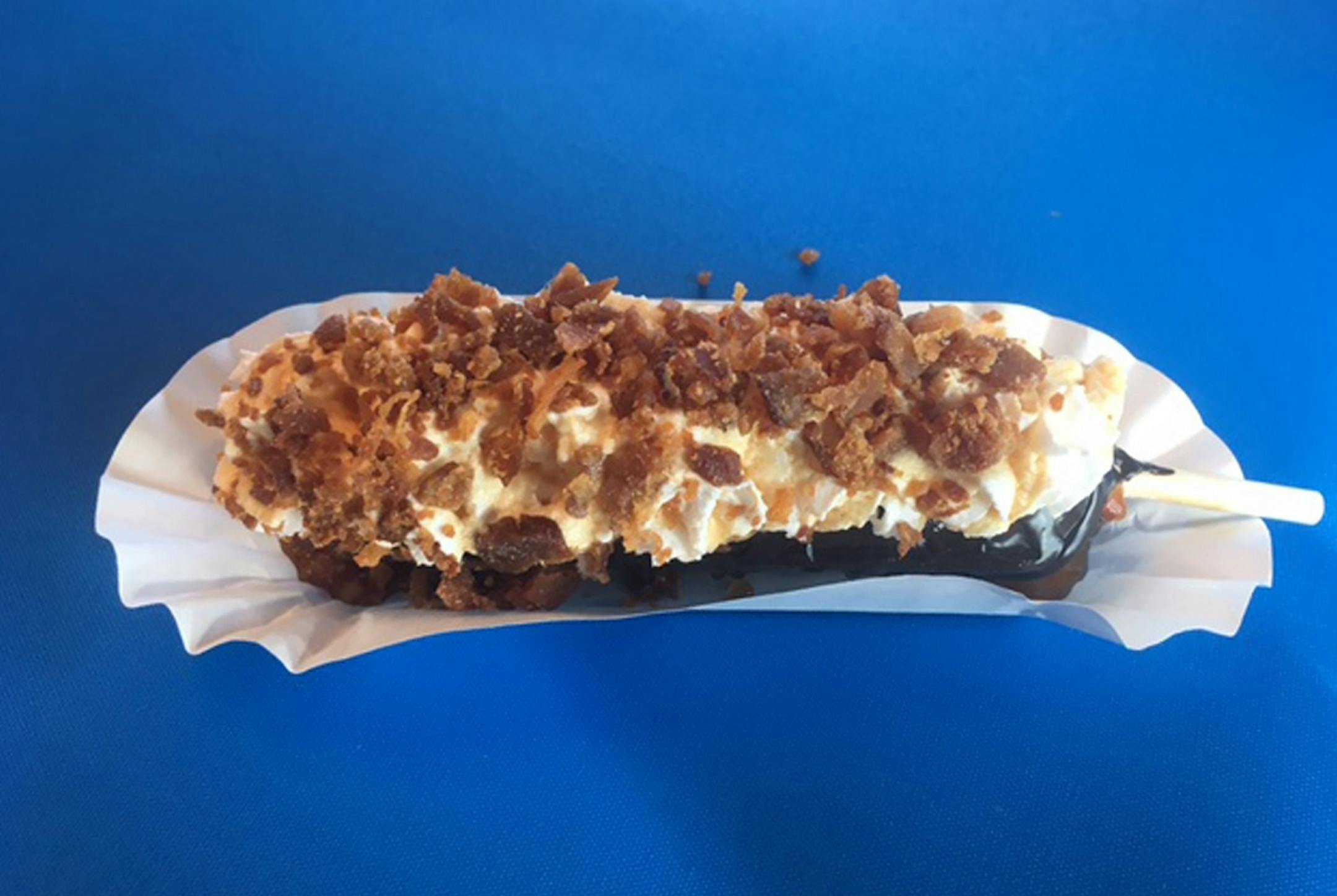 Bacon Up Pup: A Belgian waffle served on-a-stick with bacon in the batter, dipped in chocolate, drizzled with maple syrup, and topped with whipped cream and bacon. At Granny's Kitchen Fudge Puppies on the east side of Underwood St. between Dan Patch & Carnes avenues, outside the Food Building.