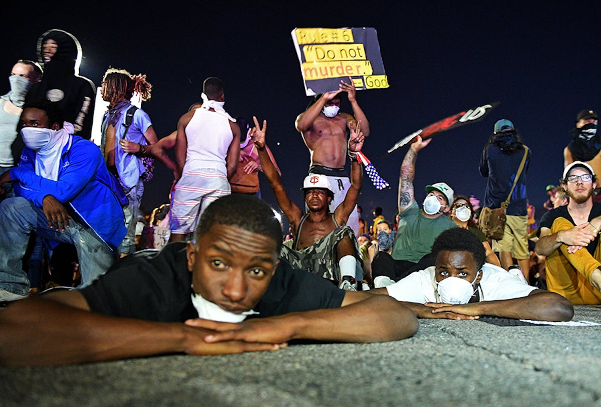 Protesters laid and sat on the ground in front of the police line on I-94 near the Dale St. exit on Saturday night.