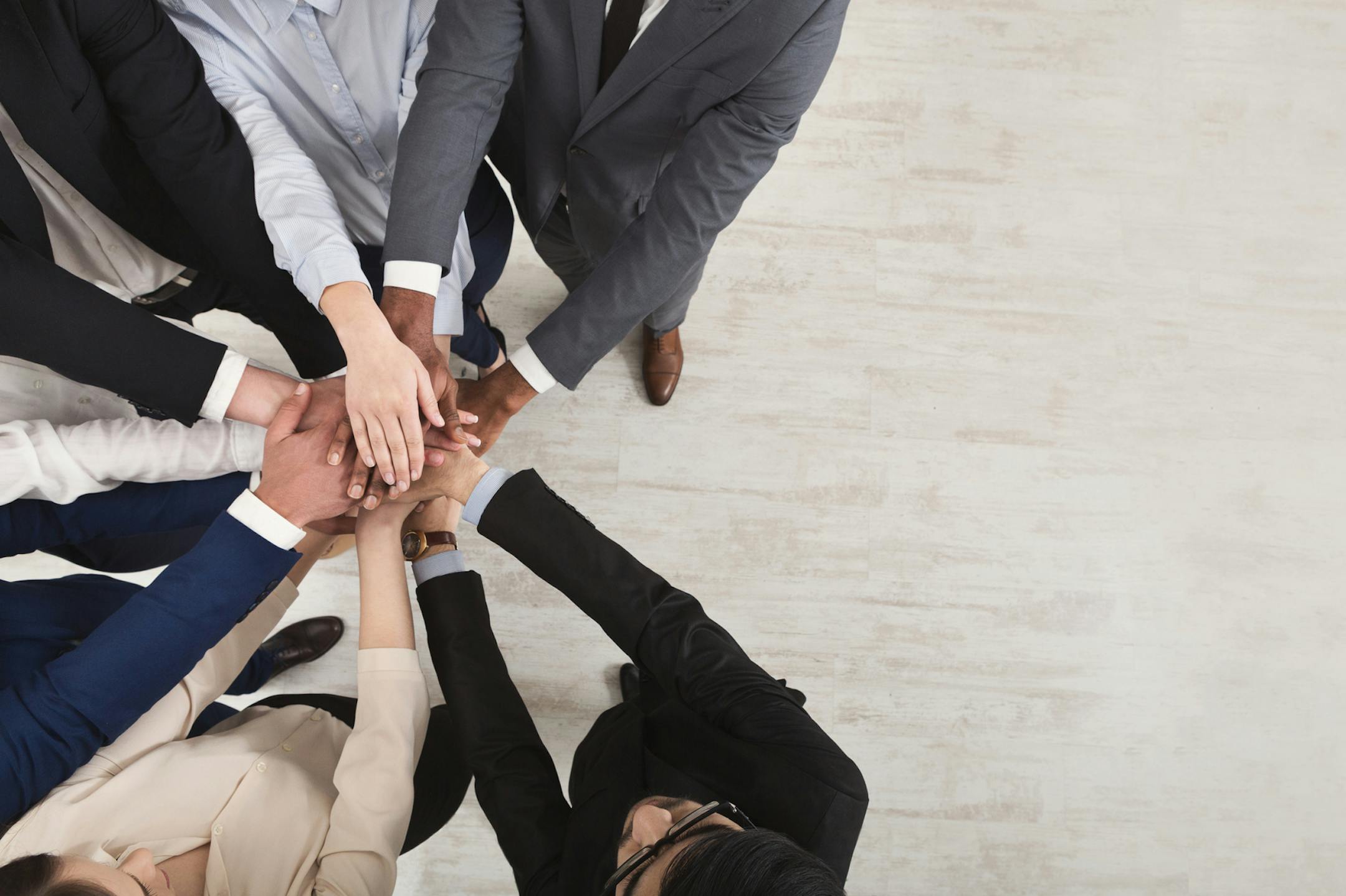 United coworkers standing with their hands together in modern office, celebrating victory, top view, teambuilding and unity , copy space