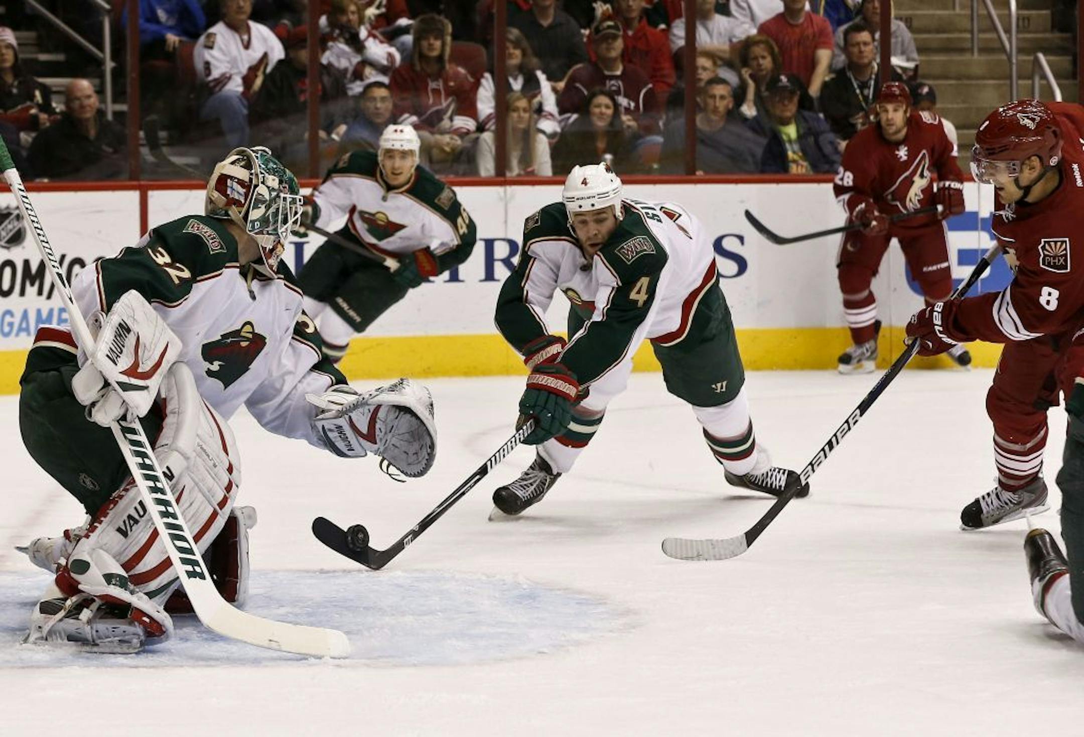 Clayton Stoner (4) makes a save on the puck on a shot from the Coyotes' Matthew Lombardi (8) as the Wild's Niklas Backstrom (32) looks on.