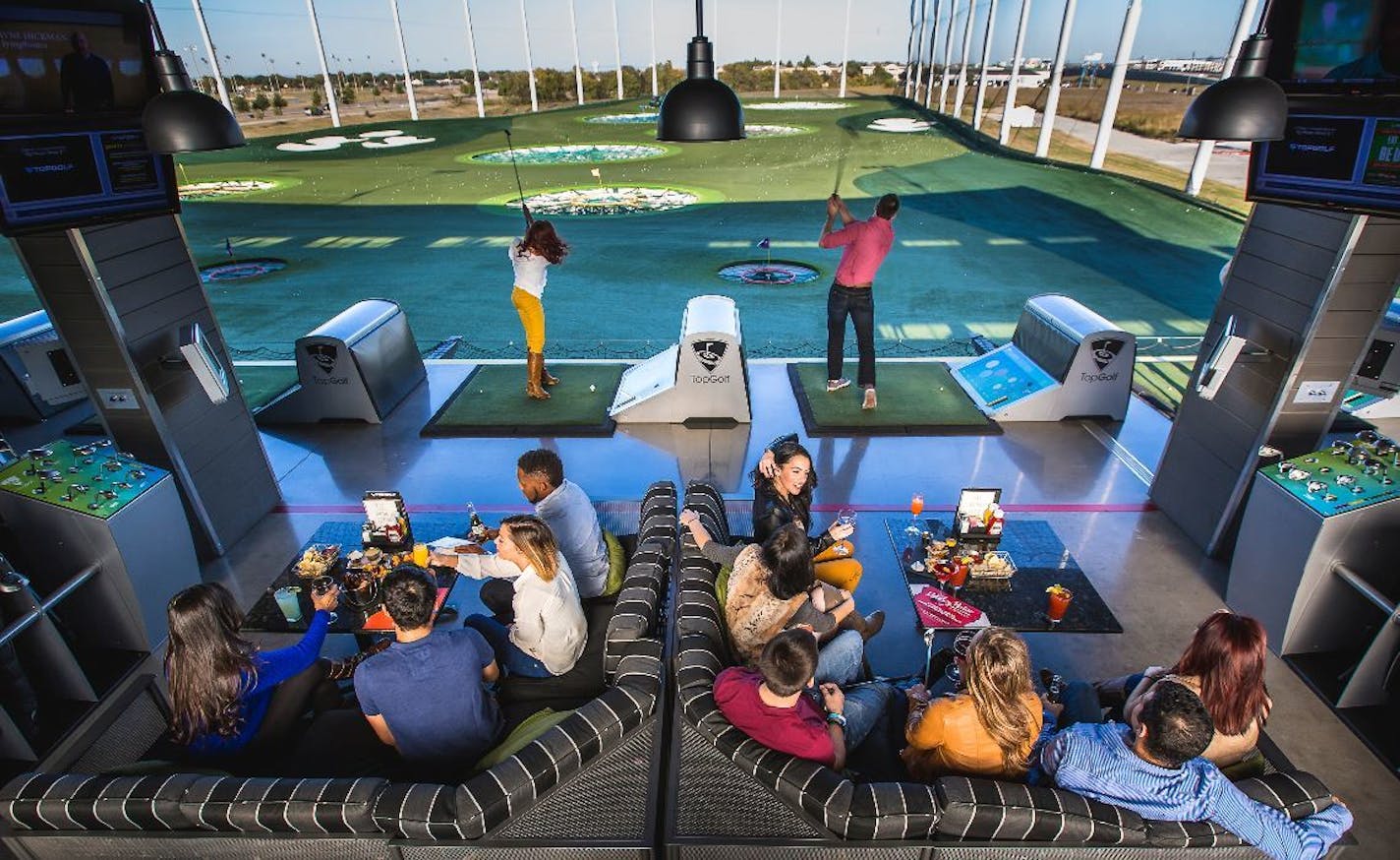 Customers relax and play at a Topgolf center.