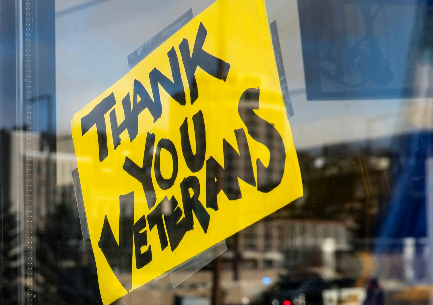 Members of the Duluth Honor Guard and local veterans were reflected in the glass of the parking booth as they marched past Amsoil Arena as part of the Duluth Veterans Day march.]