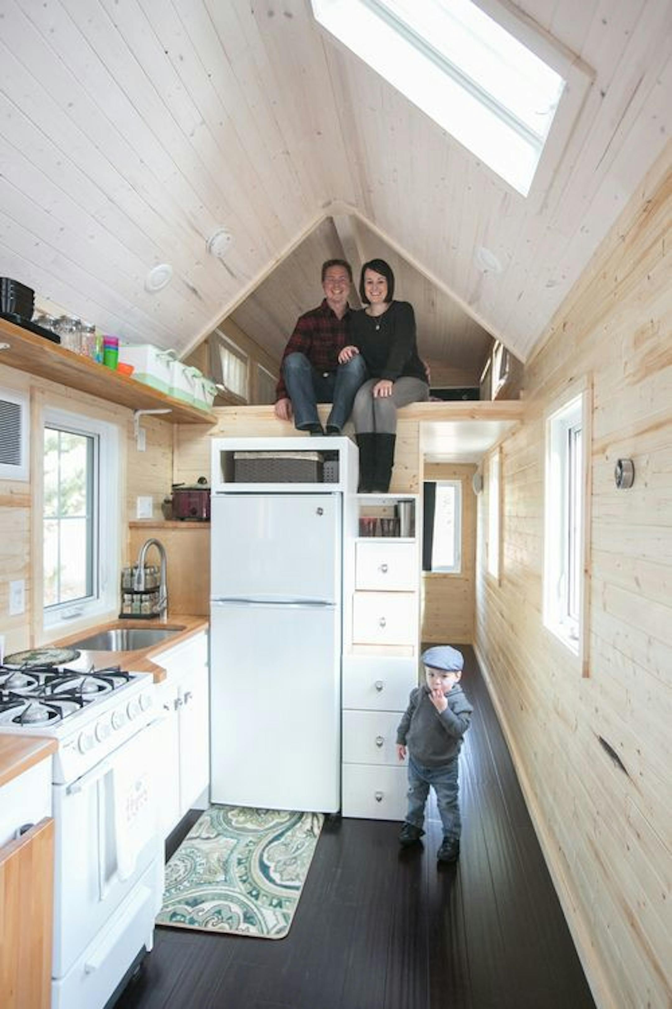 Finn Hogan stands near the pantry that doubles as a stairs to the sleeping loft where Zac and Caitlin Hogan are seated.