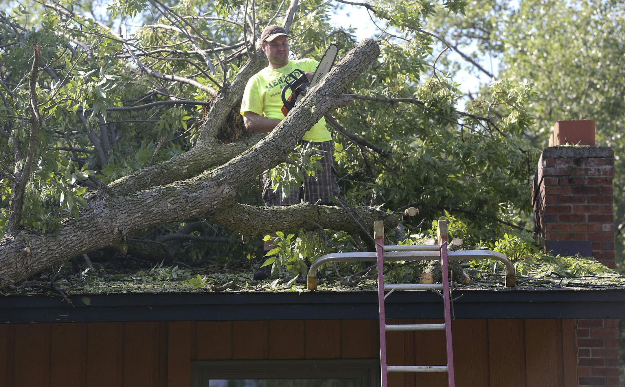 BEing a good neighbor, Jason Berg worked on cutting branches of a tree that fell on his neighbor Bill Winter's house in Bloomington Park Min., Wednesday, August 7, 2013. ] (KYNDELL HARKNESS/STAR TRIBUNE) kyndell.harkness@startribune.com