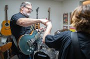 Dave Annis and his son, both wearing Trans Action Apparel shirts, bump fists during a jam session at their Minnetonka home.