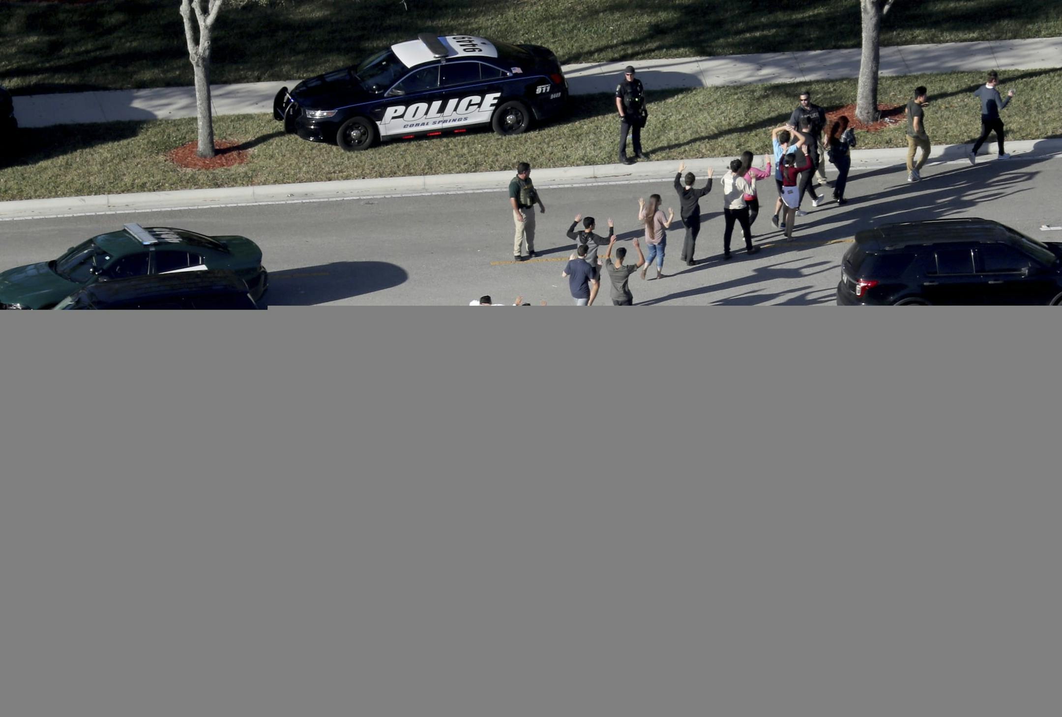 FILE - In this Feb. 14, 2018 file photo, students hold their hands in the air as they are evacuated by police from Marjory Stoneman Douglas High School in Parkland, Fla., after a shooter opened fire on the campus. Students are taught to evacuate during fire alarms but lock down during school shootings. So there was confusion Wednesday when a fire alarm sounded, the second one that day at the high school as 19-year-old former student Nikolas Cruz unleashed a barrage of gunfire. Head for the exits