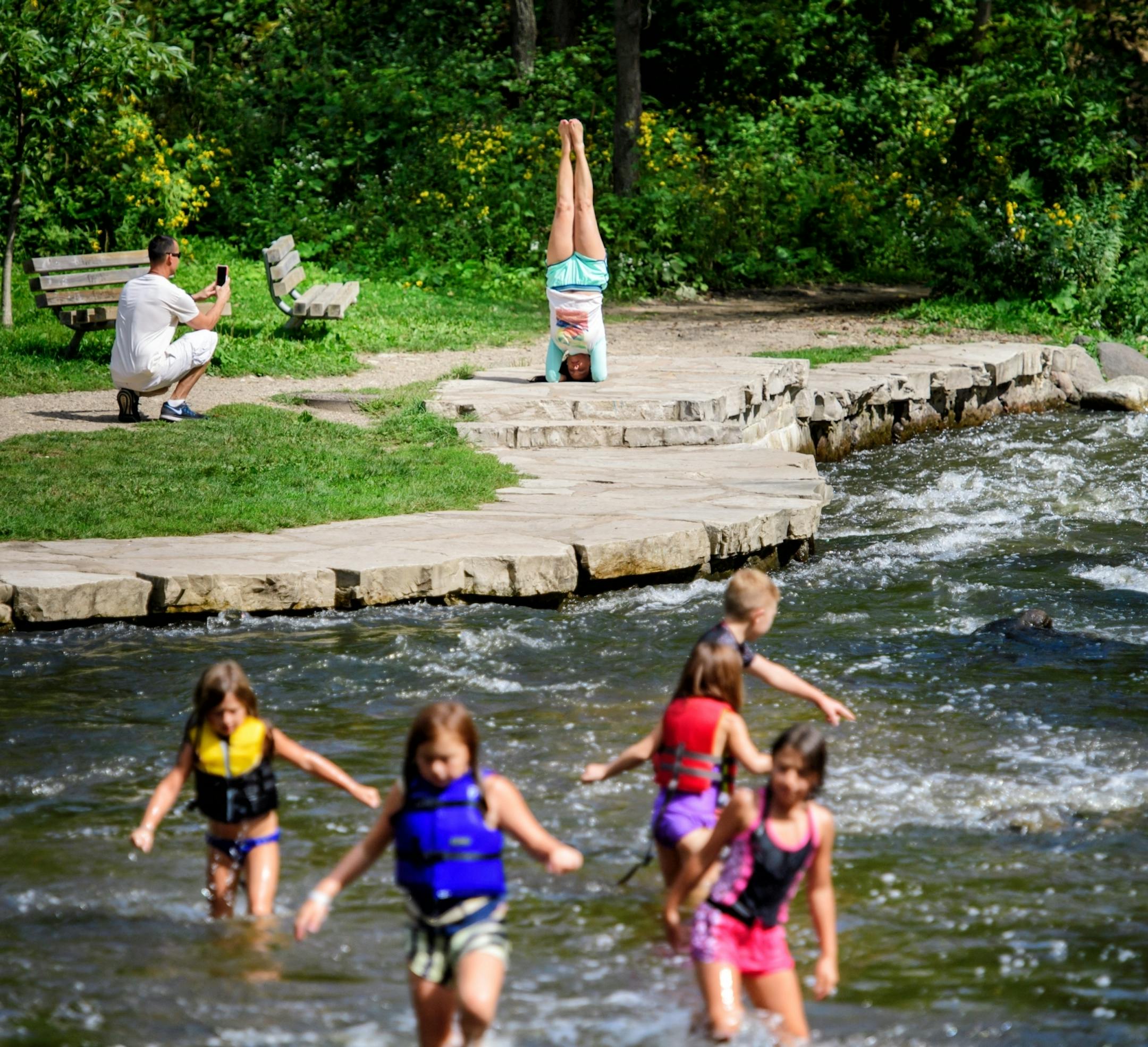 As the five Saito kids, Elizabeth, 7, Isabella 10, Alexandra, 9 Madelyn, 6 and Lincoln, 12 played in the swiftly moving waters below Minnehaha Falls, Noris Jimenez practiced her yoga moves. She is an instructor and her husband Augustin photographed her. They are originally from Puerto Rico.