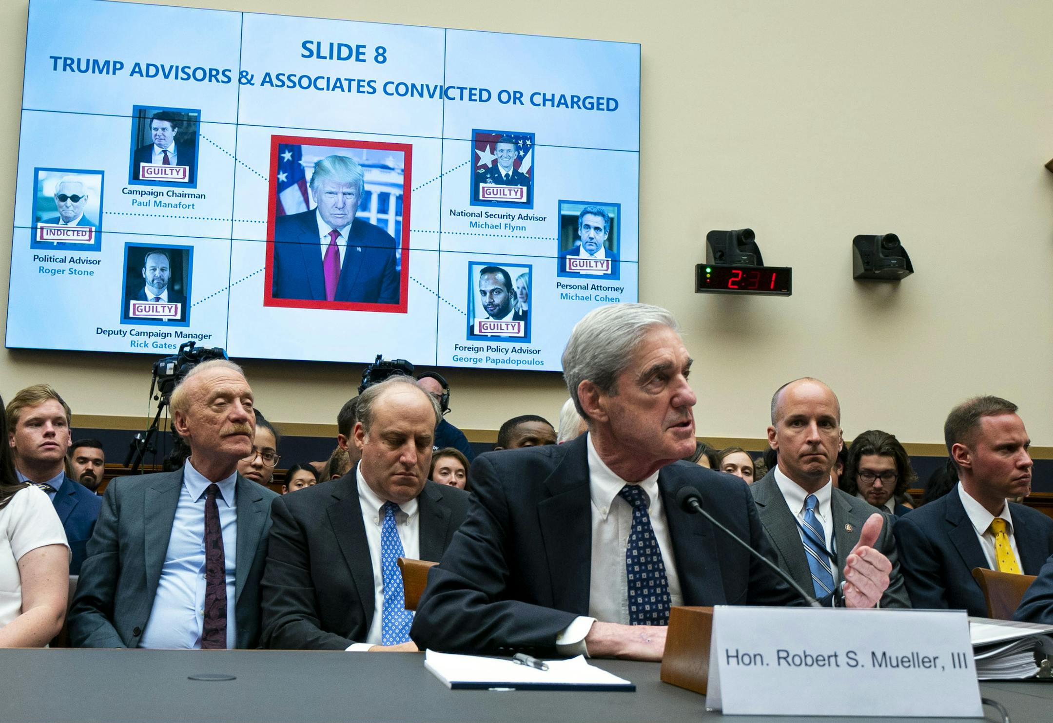 A slide is displayed on a video monitor as former Special Counsel Robert Mueller, center, testifies before the House Intelligence Committee in Washington on Wednesday, July 24, 2019. Looking on at right is Aaron Zebley, a former member of the special counsel investigation. (Doug Mills/The New York Times)