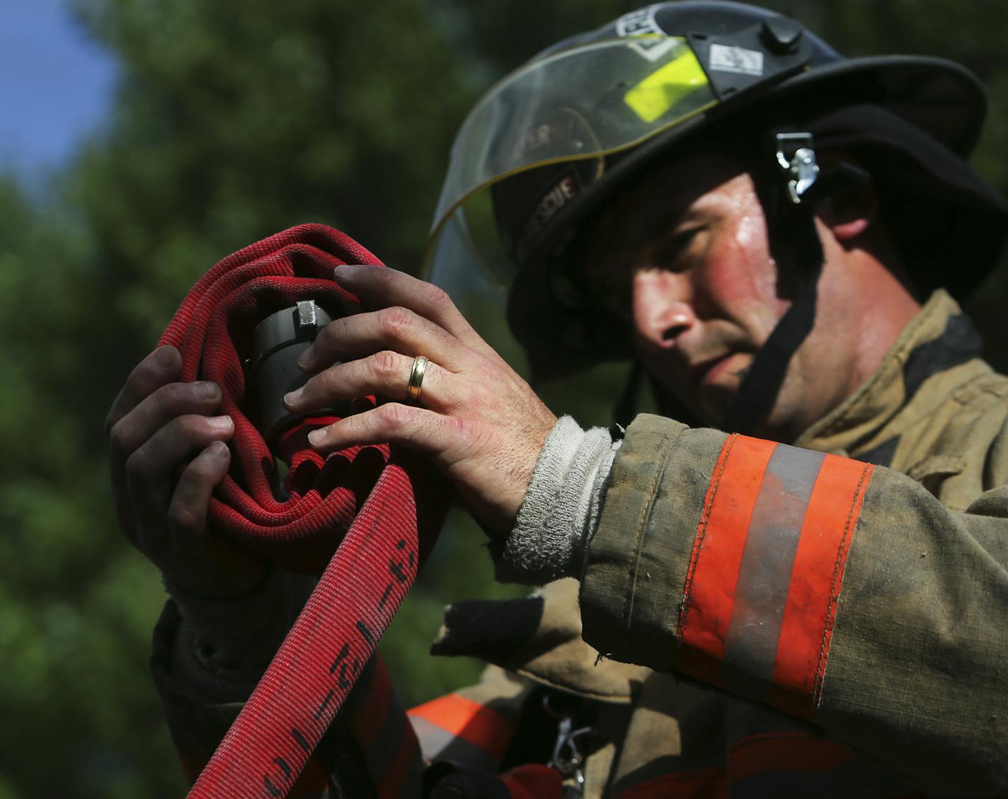 Stillwater, Minn., firefighter Brad Junker rolls up a fire hose.