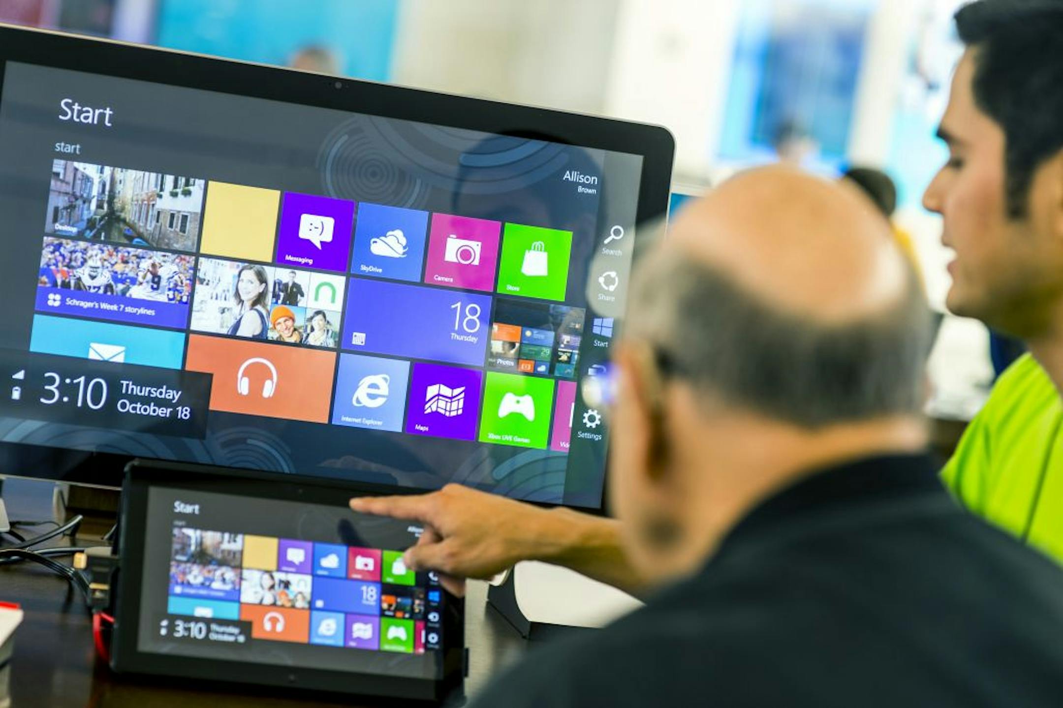 An employee at a Microsoft store, right, explains the new Windows 8 operating system on a tablet in Bellevue, Wash., Oct. 18, 2012. Windows 8's new design, which features many bold changes, is likely to cause some head-scratching when it goes on sale this Friday.
