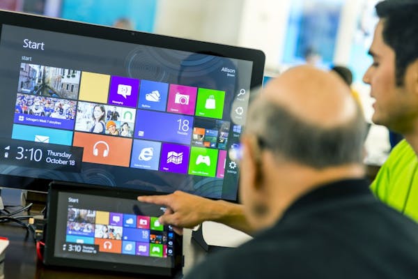 An employee at a Microsoft store, right, explains the new Windows 8 operating system on a tablet in Bellevue, Wash., Oct. 18, 2012. Windows 8's new de