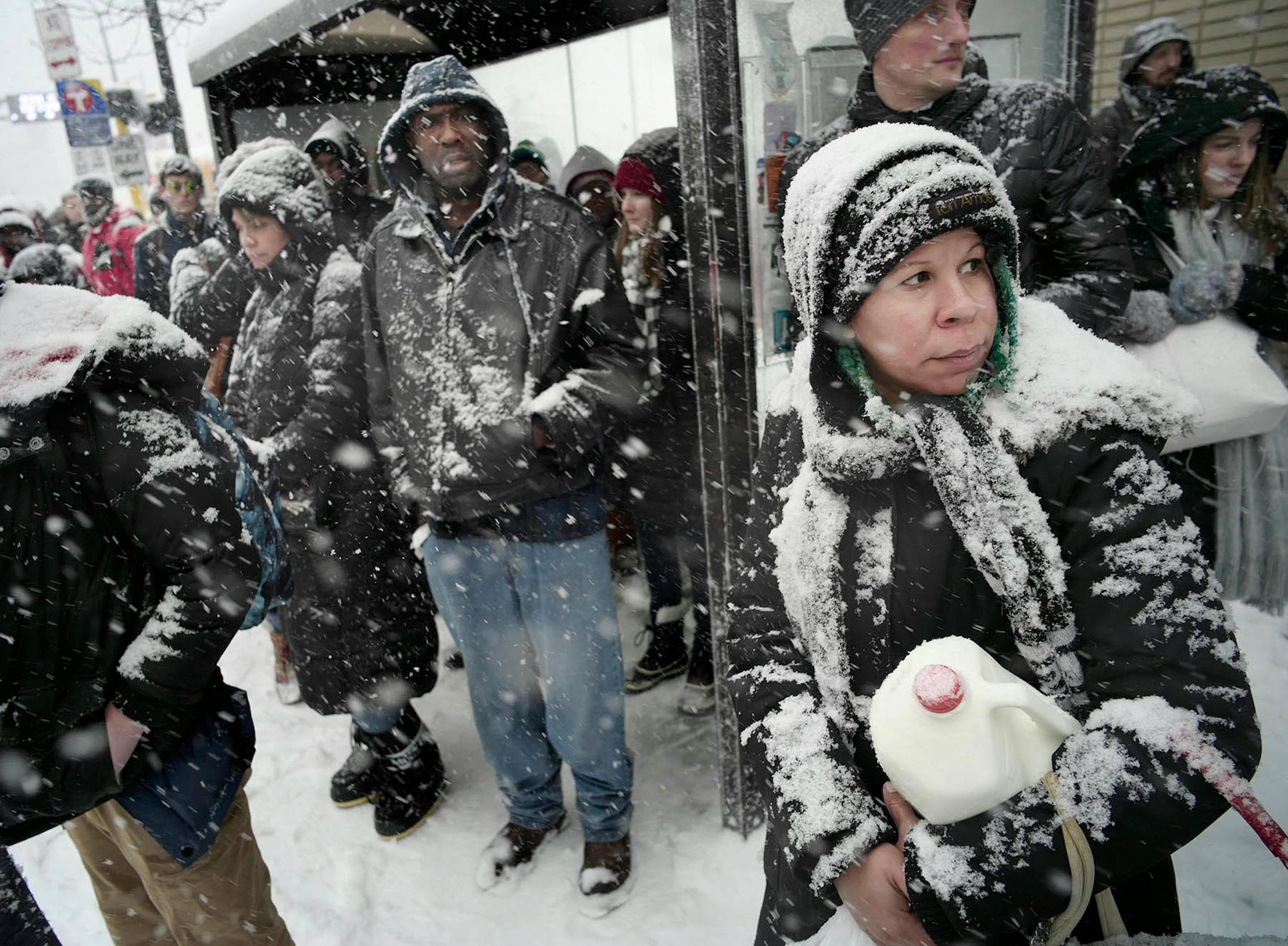 Commuters downtown waited for the bus early in the afternoon in the hope of beating the bad weather including Timmy Johnson, far right, who picked up some milk at Target. She is grateful to have the next two days off.