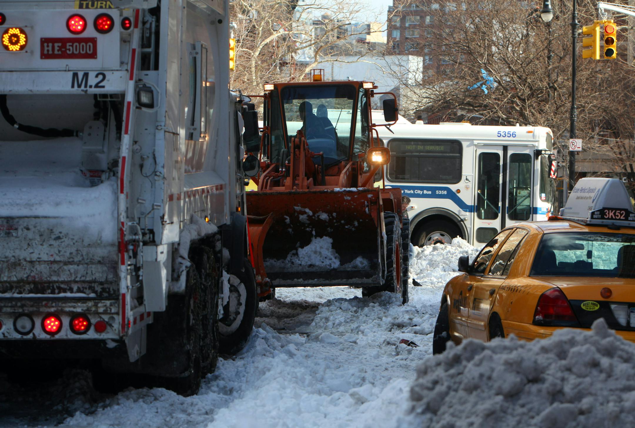 A sanitation plow removes snow to free both a garbage plow truck and taxi that were stuck in the snow as an MTA bus passes in New York on Dec. 28, 2010. After New York was hit with a blizzard leaving more than 20 inches of snow, Mayor Michael Bloomberg said on Tuesday that the city was doing all it could to clear the streets, but he couldn’t say when the work would be finished. (Nicole Bengiveno/The New York Times) ORG XMIT: MIN2013031810072117
