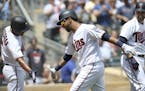 Minnesota Twins' Eddie Rosario, middle, celebrates with teammate Eduardo Escobar, left, after Rosario's three-run home run in the fourth inning of a b