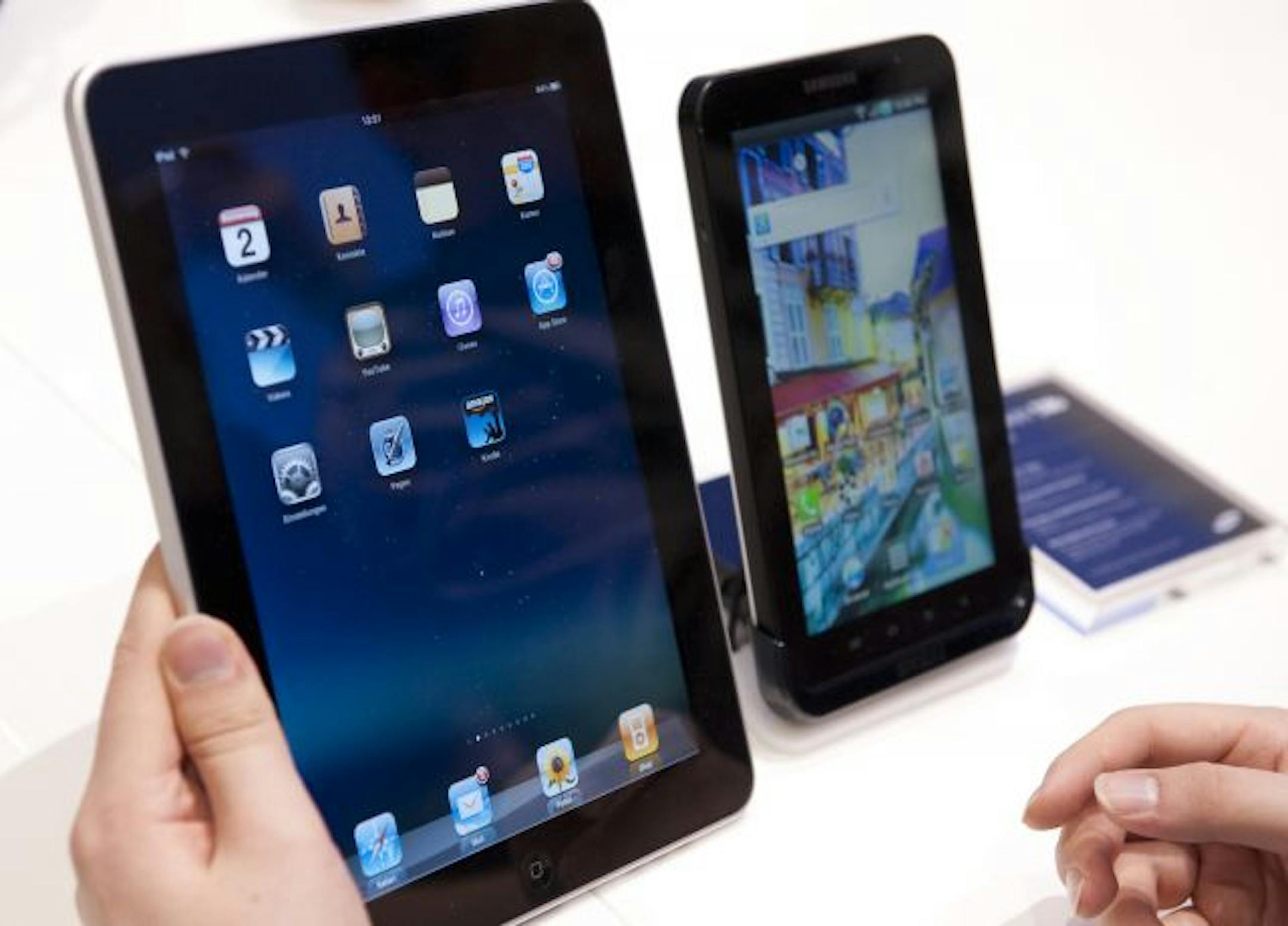 A journalist compares the new Samsung Galaxy Tab, right, a tablet computer to compete with the Apple iPad, left, at IFA, the world's largest trade fair for consumer electronics and electrical home appliances, in Berlin, Germany.