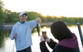 Jordan Khawaldeh holds up his first catch of the season, a large mouth bass, for his wife to photograph him on Lake Harriet on Saturday.
ALEX KORMANN
