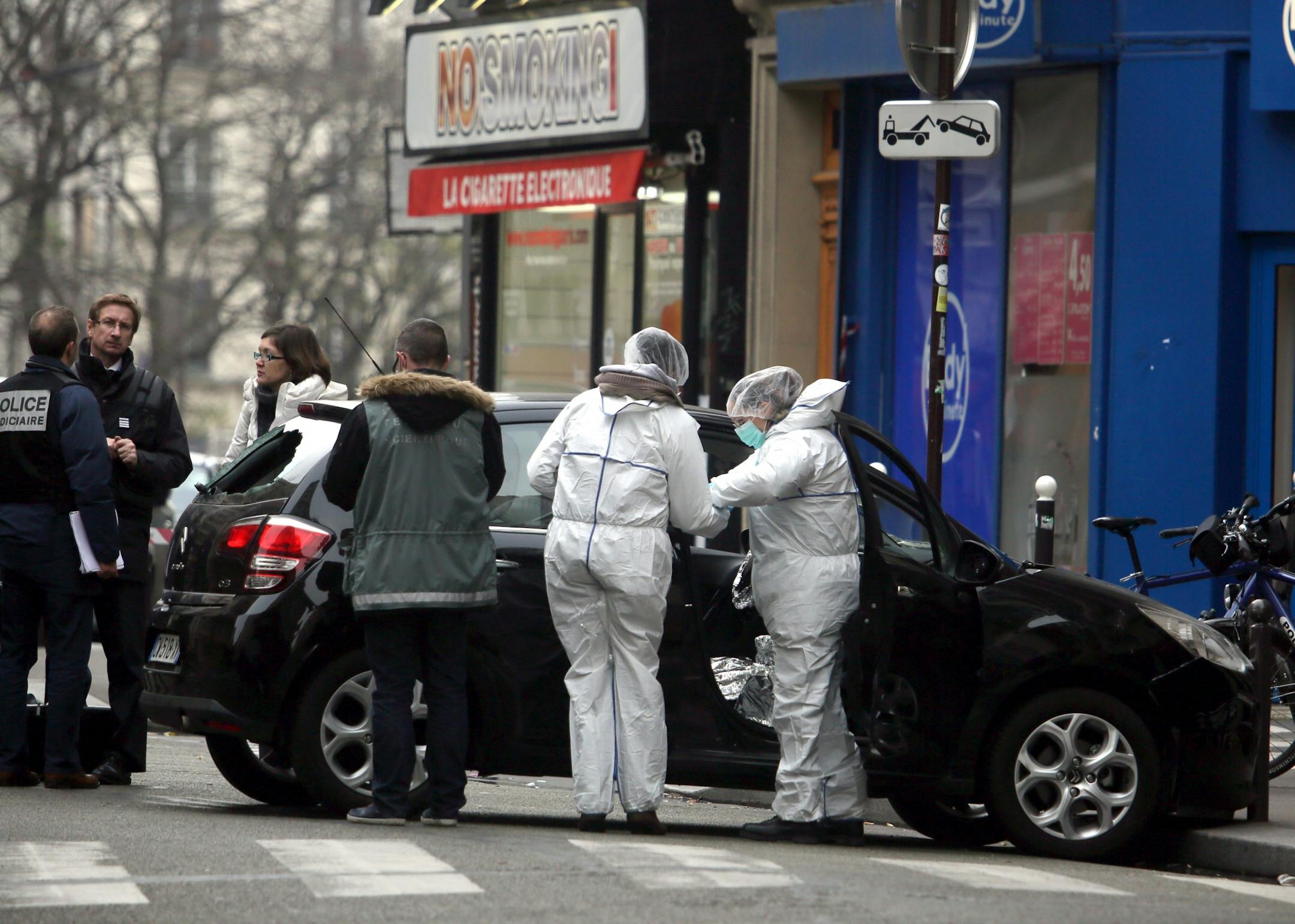 Forensic experts examine the car believed to have been used as the escape vehicle by gunmen who attacked the French satirical newspaper Charlie Hebdo's office, in Paris, France, Wednesday, Jan. 7, 2015. Masked gunmen stormed the offices of a French satirical newspaper Wednesday, killing at least 11 people before escaping, police and a witness said. The weekly has previously drawn condemnation from Muslims.