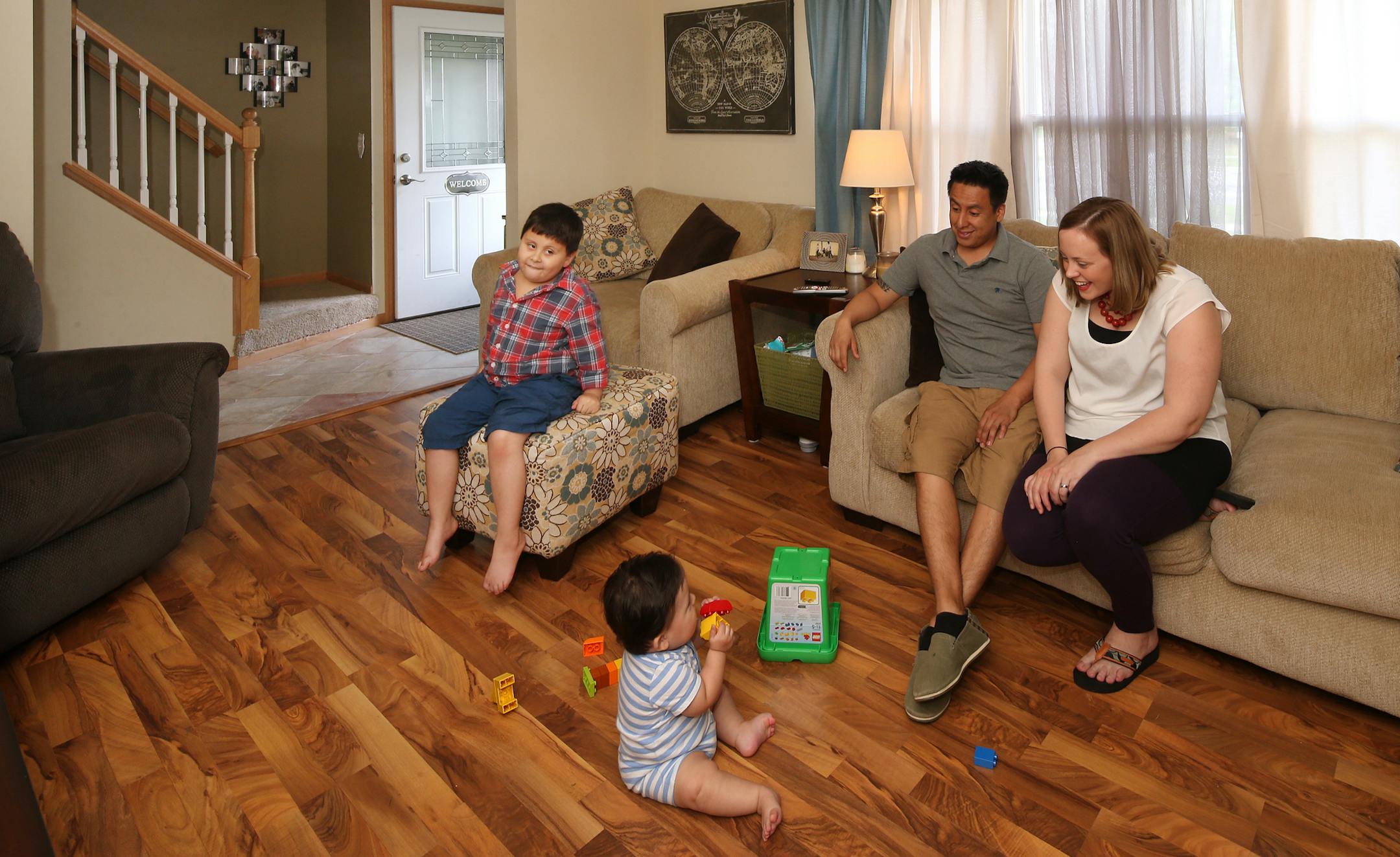 Javier Arias (dad), Emily Arias (mom), Lucas Arias (6), and Jonas Arias (baby) in the livingroom of their home. ] JOELKOYAMA‚Ä¢jkoyama@startribune Brooklyn Park, MN on June 2, 2014. Brooklyn Park has bought and is flipping 200 homes, to attract young families and other new buyers to the city's housing stock.