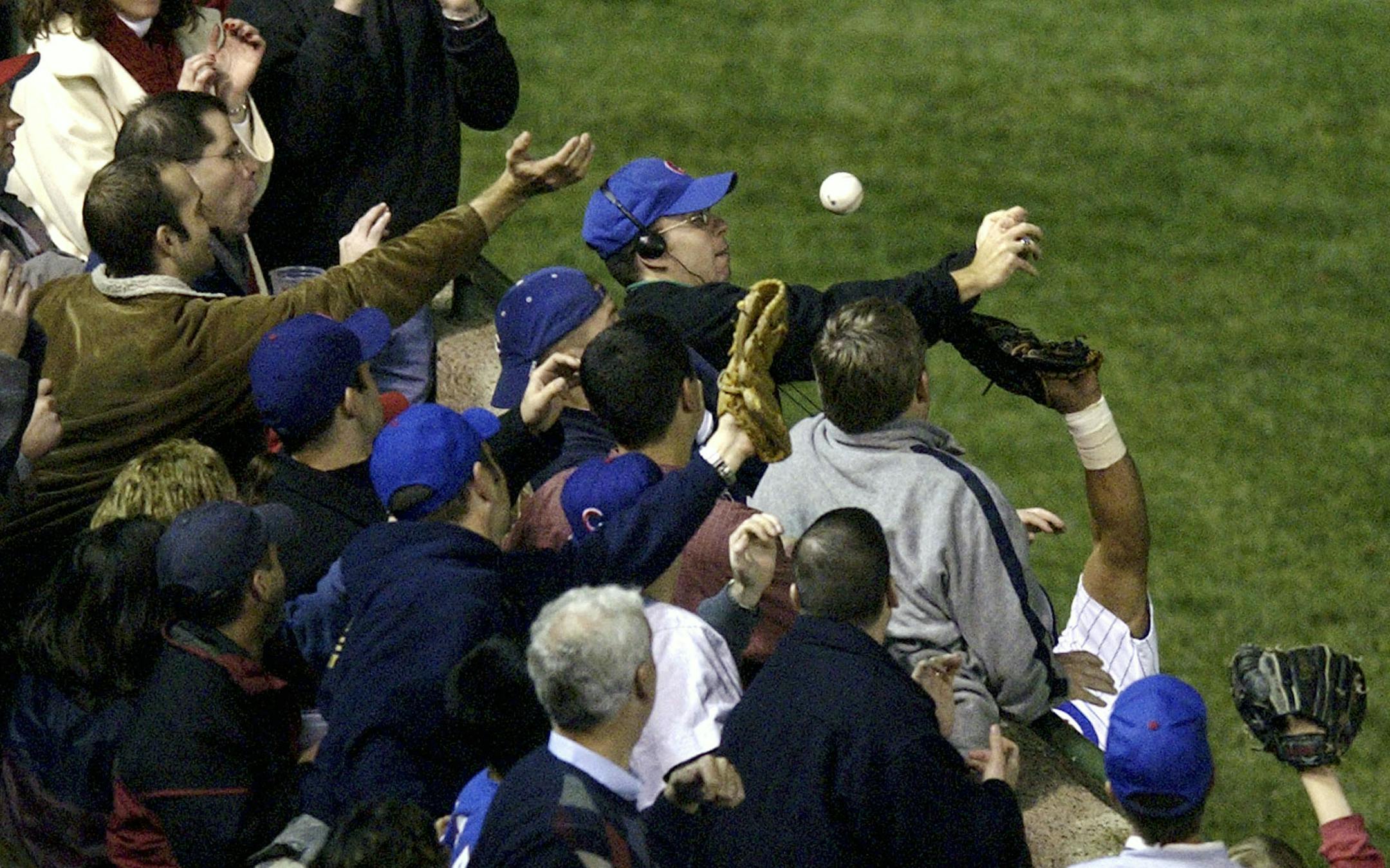 ** FILE ** In this Oct. 14, 2003 file photo, Chicago Cubs left fielder Moises Alou's arm is seen reaching into the stands, at right, unsuccessfully for a foul ball along with a fan identified as Steve Bartman, left, wearing headphones, glasses and Cubs hat, during the eighth inning against the Florida Marlins in Game 6 of the National League Championship Seriesin Chicago. (AP Photo/Morry Gash, File) ORG XMIT: MIN2017080315124834