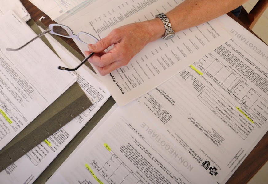 Medical bills are spread out on the kitchen table of a cancer patient in Salem, Va.