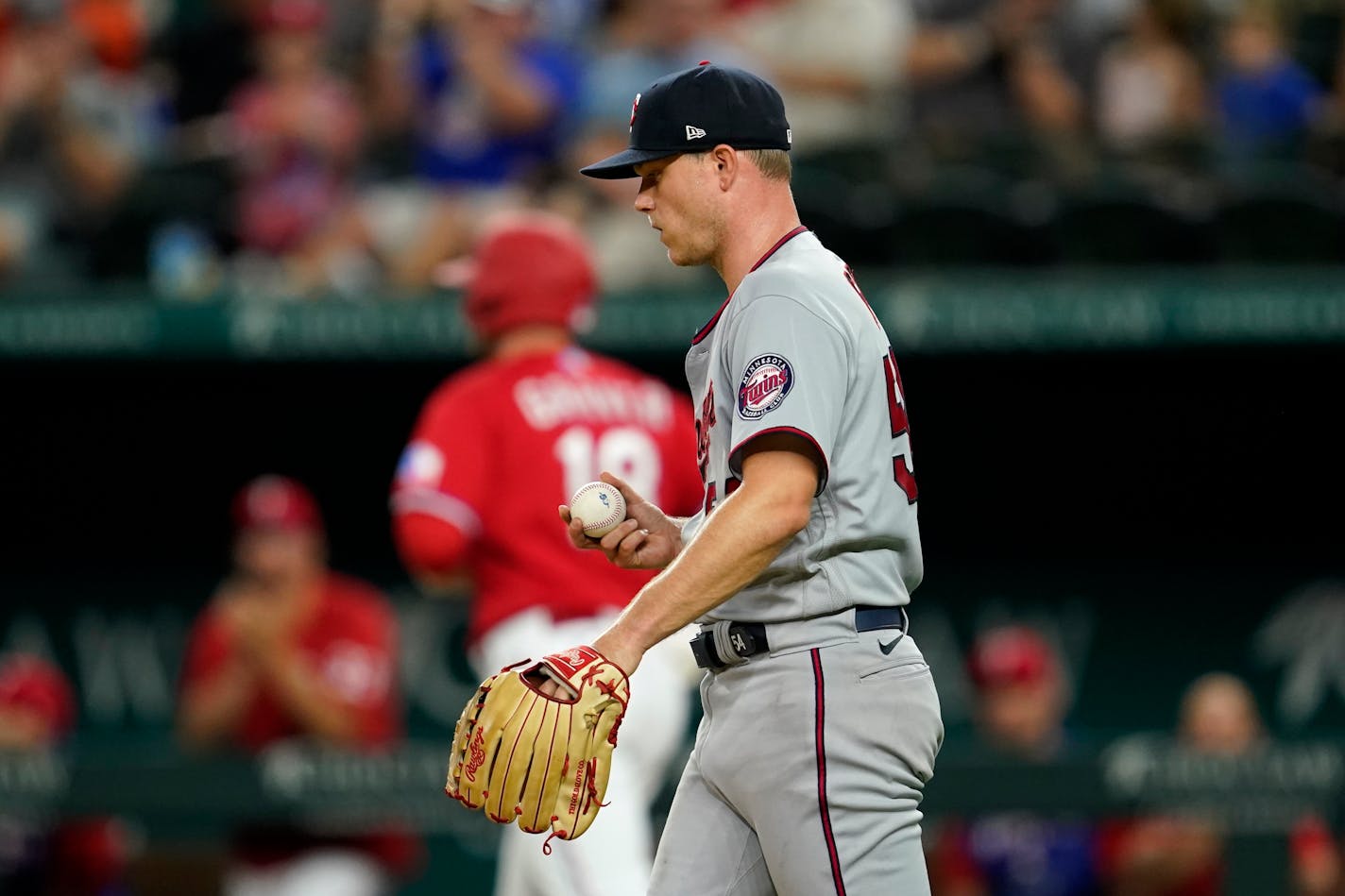 Twins starting pitcher Sonny Gray walks back to the mound as the Rangers' Mitch Garver takes first base after being hit by a pitch in the fifth inning