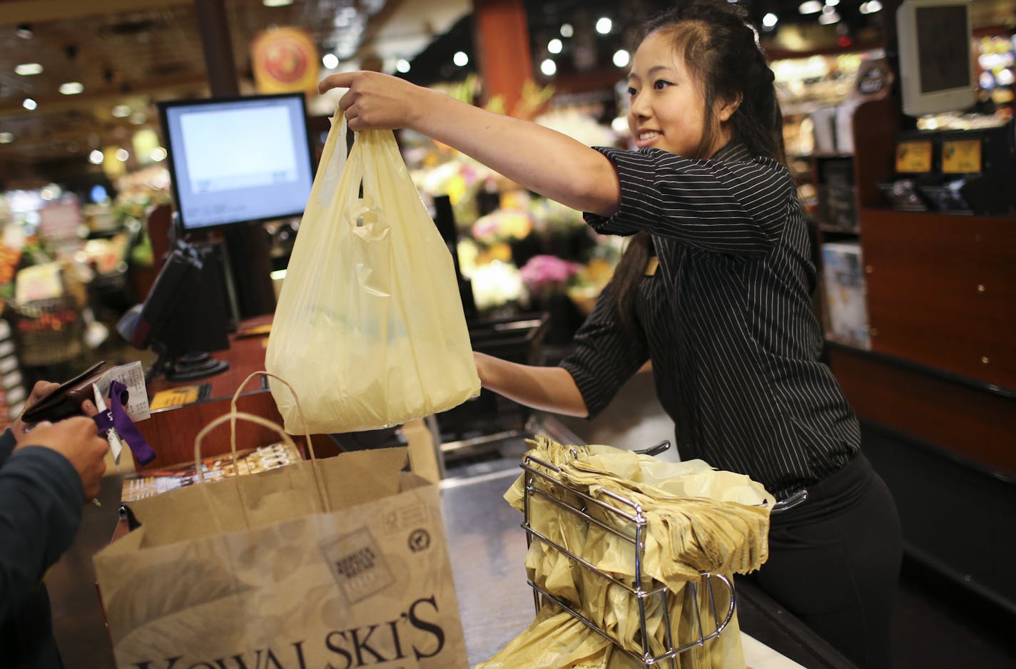 Hannah Peterson handed a plastic bag of groceries to a customer at Kowalski's in Uptown in Minneapolis, on Thursday, July 23, 2015.