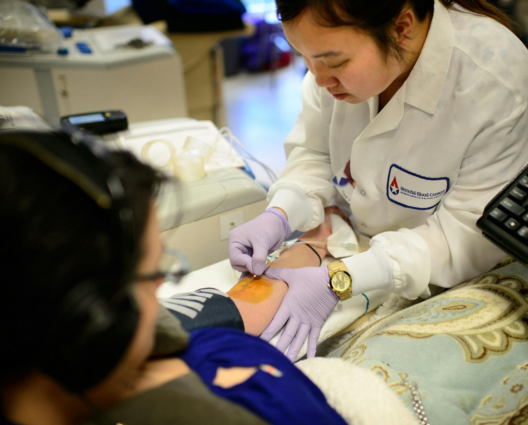 Memorial Blood Centers phlebotomist Youa Vang prepared Cathryn Heimerdinger for a blood donation. Memorial Blood Centers, a member of Blood Centers of America which announced a merger with GSABC-Cooperative Corp The merger of the two organizations creates the nations largest blood supply network in the U.S. ] GLEN STUBBE * gstubbe@startribune.com Tuesday, April 1, 2014.