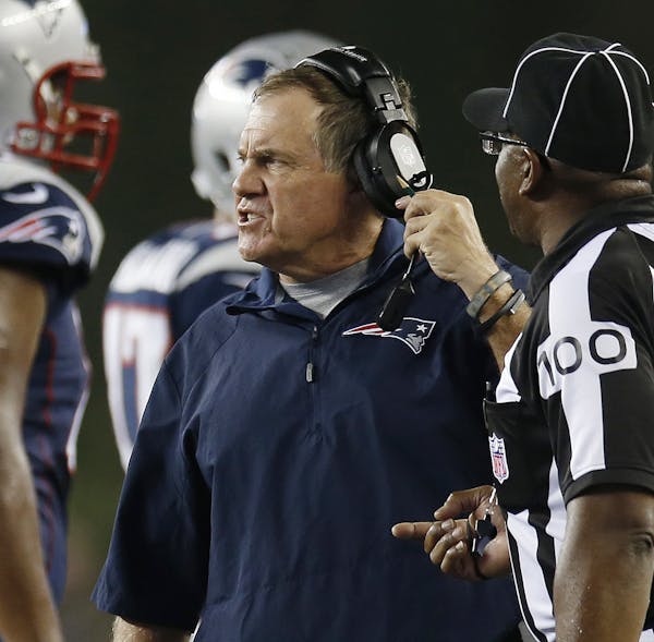 New England Patriots coach Bill Belichick speaks as line judge Tom Symonette (100) listens in the first quarter of the Patriots' NFL football game aga